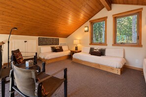 A cozy room with two beds, a desk, and a chair, featuring wooden beams and large windows. - Montaska Cabin 2 Bedroom Cabin (Leavenworth)
