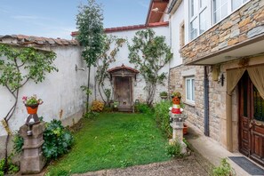 A courtyard with a wooden door, potted plants, and a stone wall.