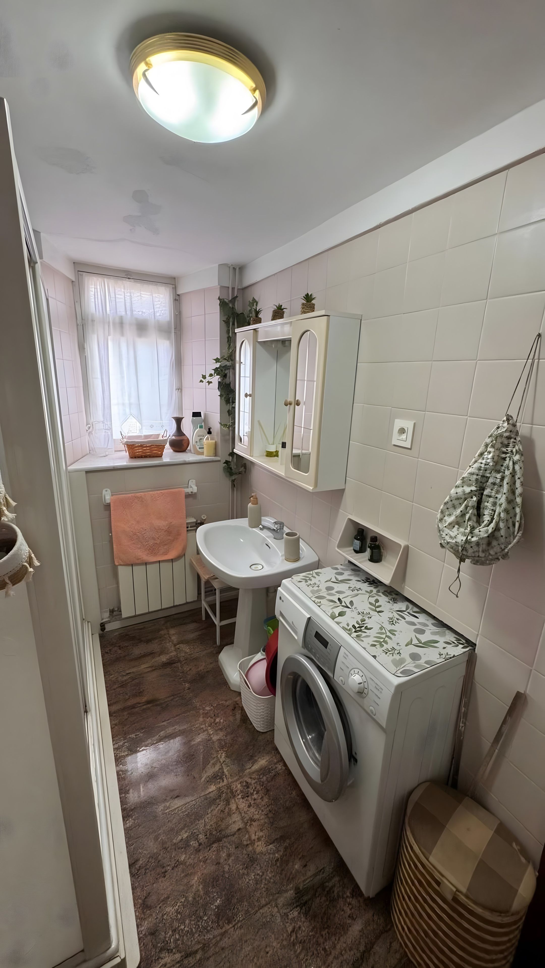 Une petite salle de bain comprenant un lavabo, un miroir et un lave-linge.