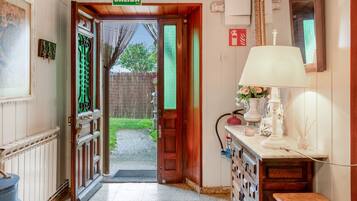 Passadís amb una porta de fusta que porta a l'exterior, amb la inscripció 'SALIDA', un radiador, una taula petita amb una làmpada i un extintor penjat a la paret.