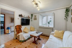 A living room with a sofa, a coffee table, a television, and a window with a view.