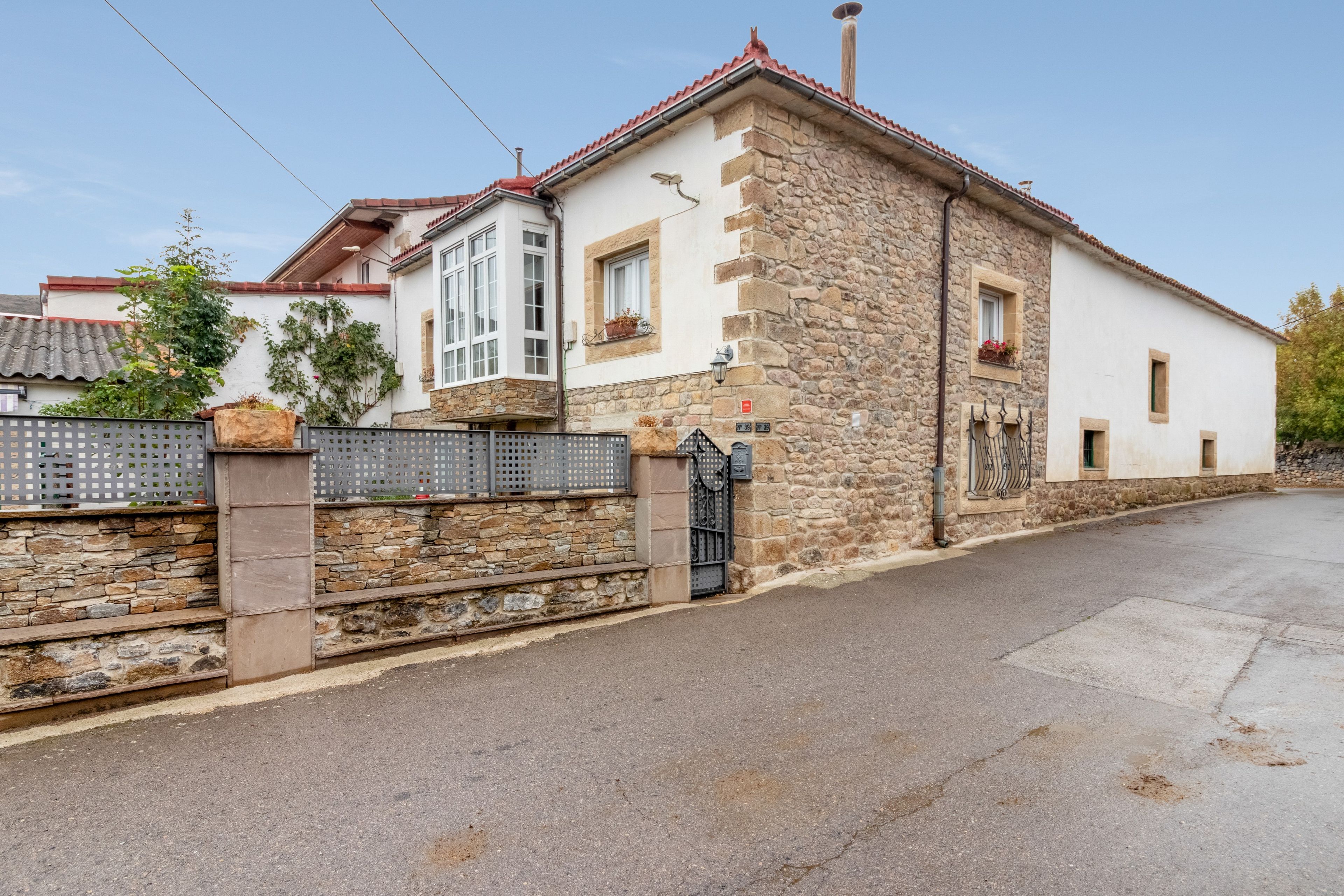A stone building with a white facade, a red-tiled roof, and a gated entrance.