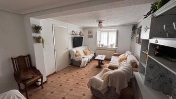 Una sala acogedora con un conjunto de sofás, una televisión y una mesa de comedor.