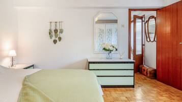 A bedroom with a bed, a dresser, a mirror, and a window with a view.