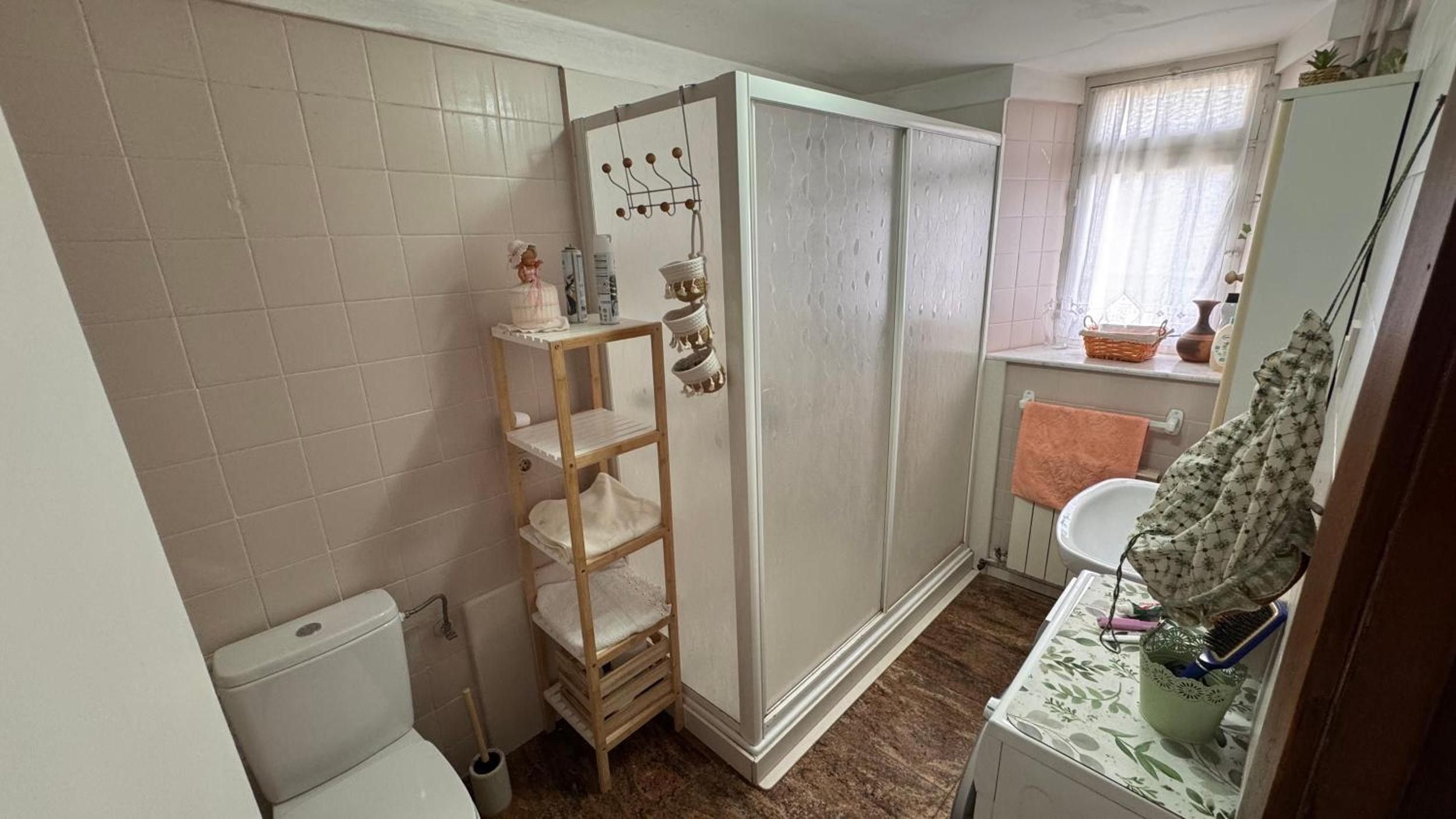 Ein Badezimmer mit Toilette, einem Holzboden mit Handtüchern, einer Dusche und einem Waschbecken mit Handtuchhalter.