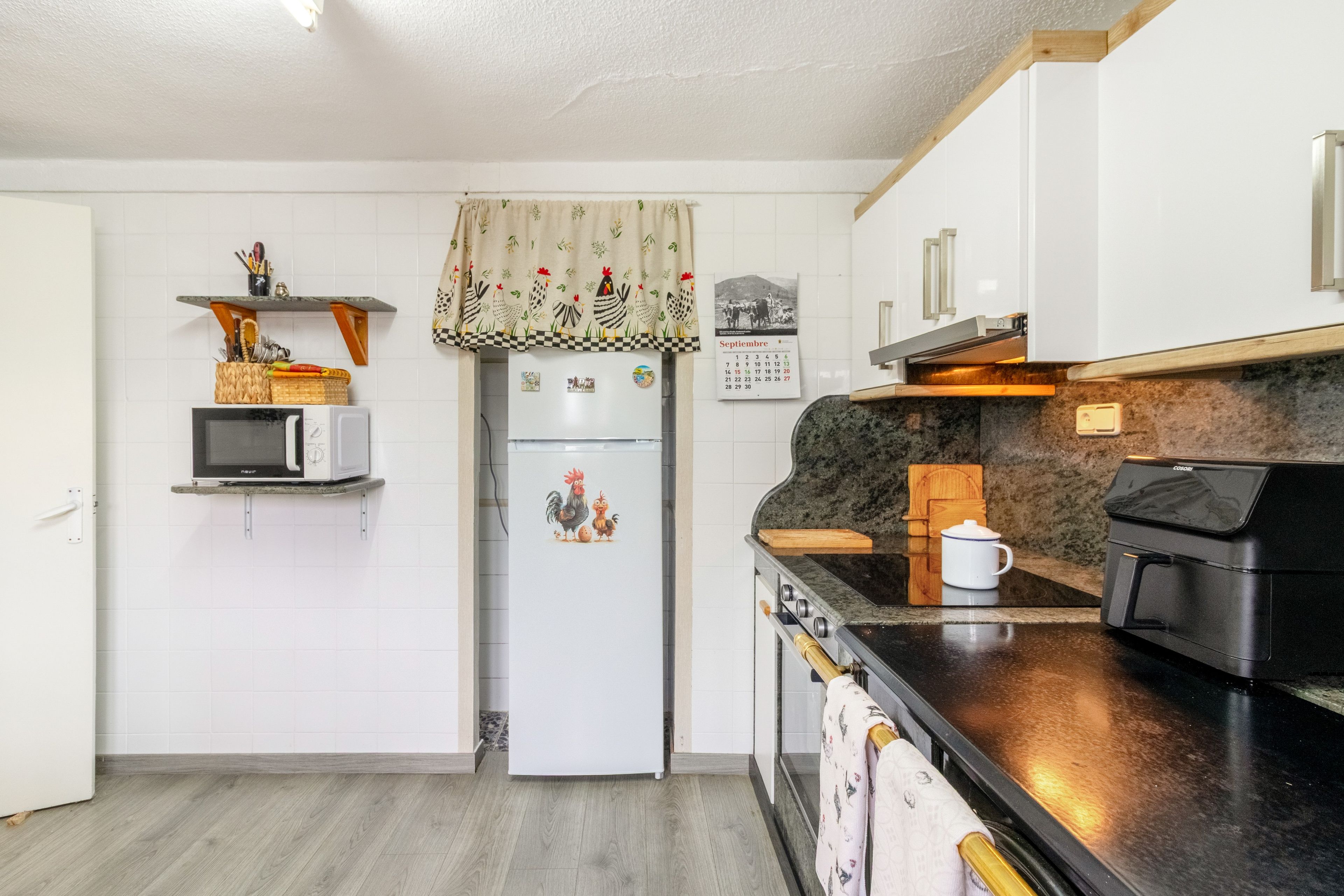 A compact kitchen with white cabinets, a microwave, a refrigerator, and a stove.