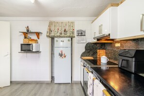 A compact kitchen with white cabinets, a microwave, a refrigerator, and a stove.