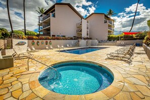 A hotel with a swimming pool, lounge chairs, and a stone-tiled deck. - Kihei Alii Kai C302 1 Bedroom Apts (Kihei)