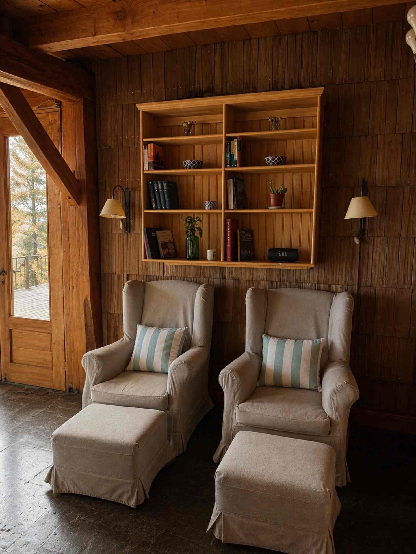 A room with two armchairs, a wooden bookshelf, and a door leading outside.