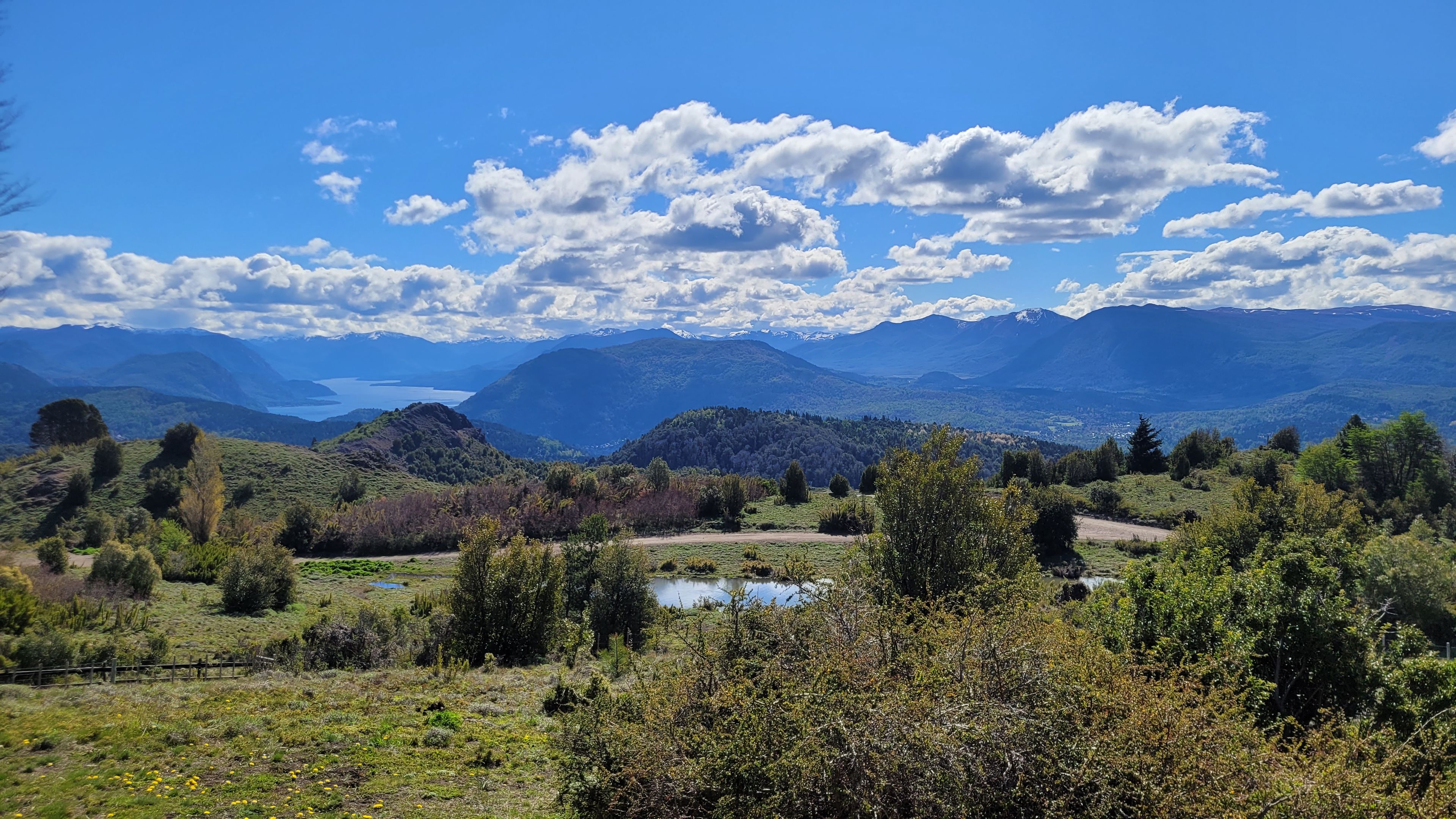 Un paisaje montañoso con un lago, árboles y cielo despejado.