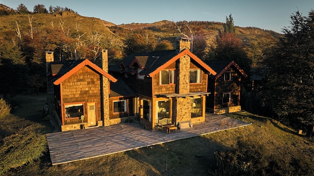 Una casa in pietra su due piani, con un patio in legno e un camino in pietra.