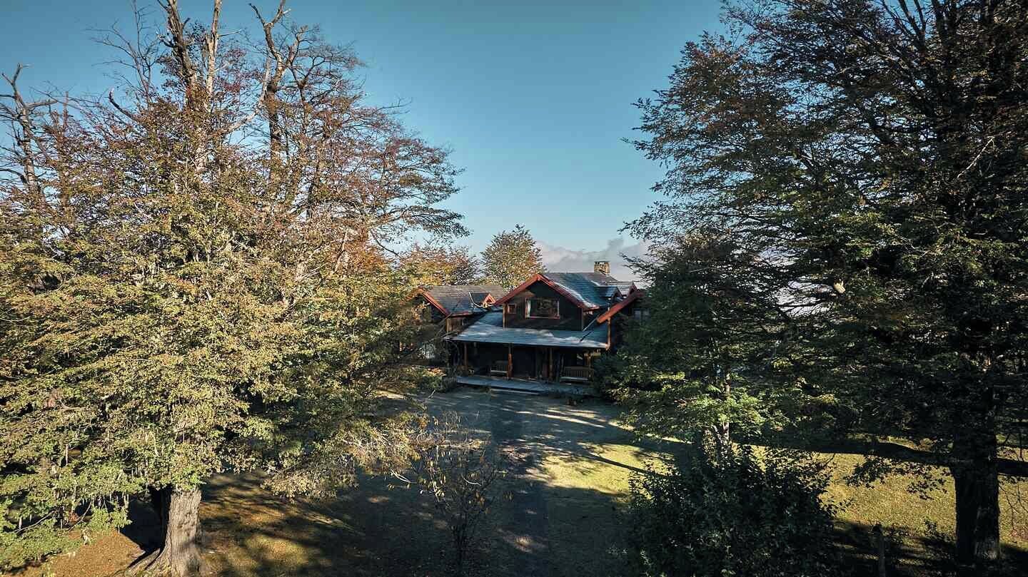 A cabin with a porch, surrounded by trees, and a clear sky.