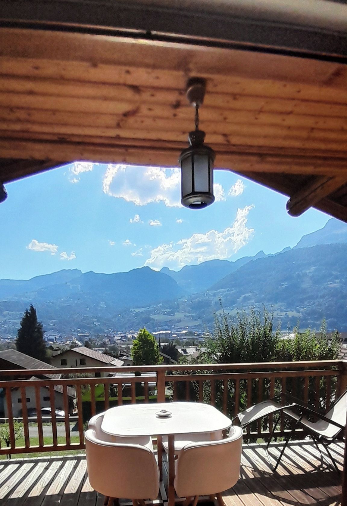 A wooden deck with a table and chairs, overlooking a mountainous landscape.