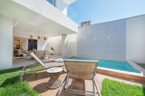 Ein moderner Poolbereich im Freien mit Liegestühlen und einer Essgruppe.