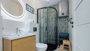 Un baño moderno con cabina de ducha de vidrio, inodoro blanco y tocador de madera con espejo.