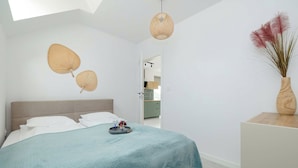 Un dormitorio con cama, mesita de noche, lámpara colgante y un adorno en la pared.