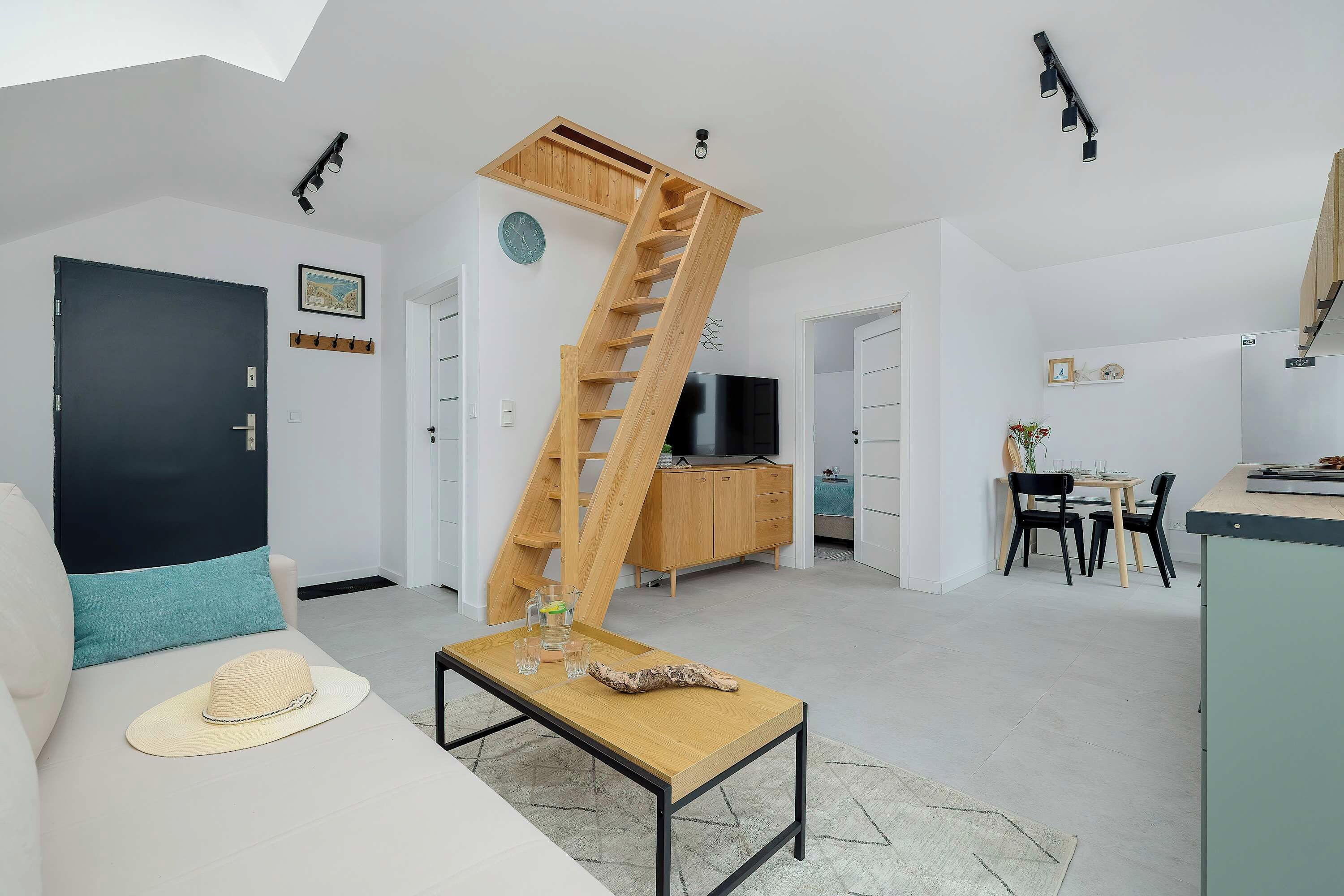 Un espace de vie moderne doté d’un escalier en bois, d’un téléviseur à écran plat et d’un coin repas.