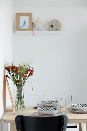 A dining table with a vase of red flowers, clear glasses, and black-and-white patterned plates. - Rusinowo | Bosmańska 2 | Cosy Apartment | Balcony | Close to the sea (Rusinowo)