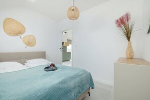 A modern bedroom with a bed, a bedside table, a vase with dried plants, and a hanging light fixture. - Rusinowo | Bosmańska 2 | Cosy Apartment | Balcony | Close to the sea (Rusinowo)
