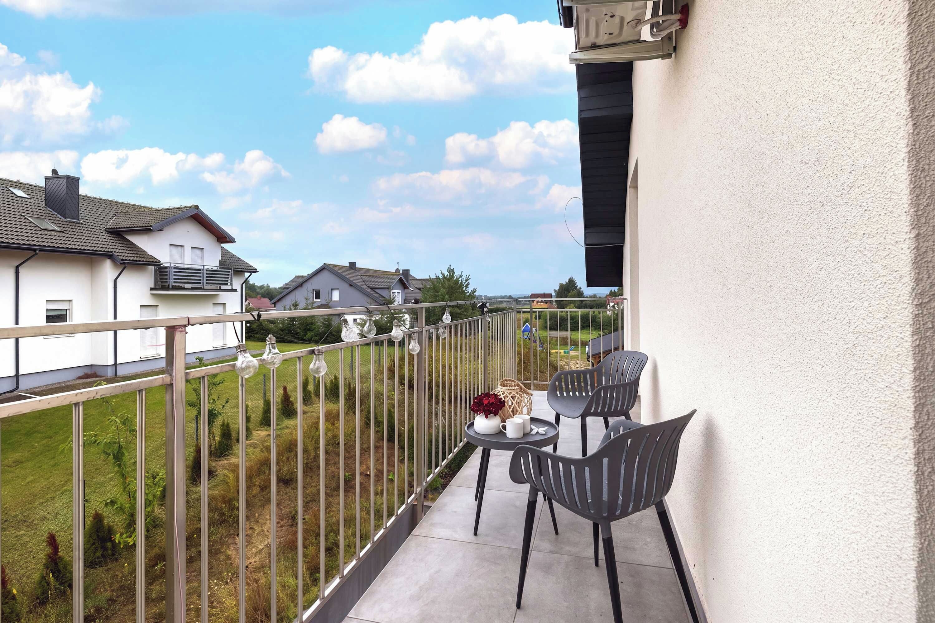 Un balcón con una mesa y sillas, con vista a una zona residencial.