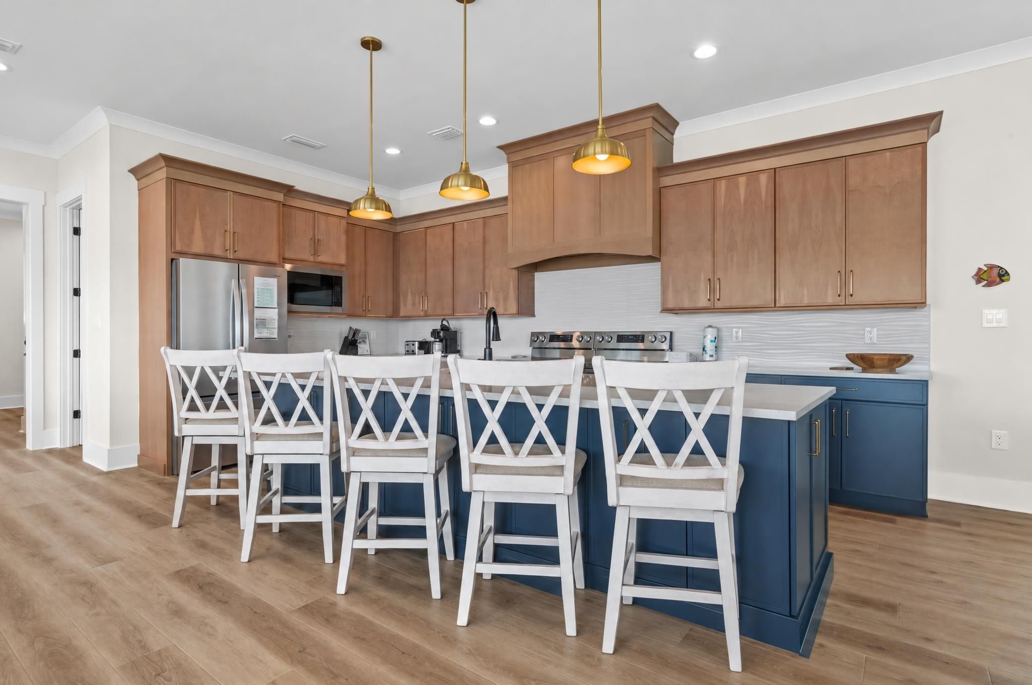 A modern kitchen with wooden cabinets, a central island with bar stools, and pendant lighting.