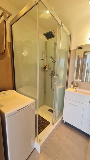 A modern bathroom with a glass-enclosed shower, a white washing machine, and a sink with a mirror. - Bright house in Porticcio for 6 people (Grosseto-Prugna)