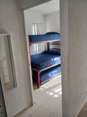 Una cama litera con colchón azul y pared blanca.