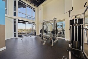 A gym with weightlifting equipment, large windows, and a view of the outdoors. - Steps to the Beach | 1BR/2BA | Resort Pools (Panama City Beach)