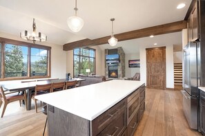 Eine geräumige Küche mit einer großen Kochinsel, Holzböden und einem Kamin aus Stein.