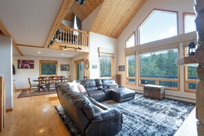 A spacious living room with a large black leather sectional sofa, wooden flooring, and a high ceiling with exposed beams. - Quandary Views of Breckenridge: Scenic Views & Mountain Comfort (Breckenridge)
