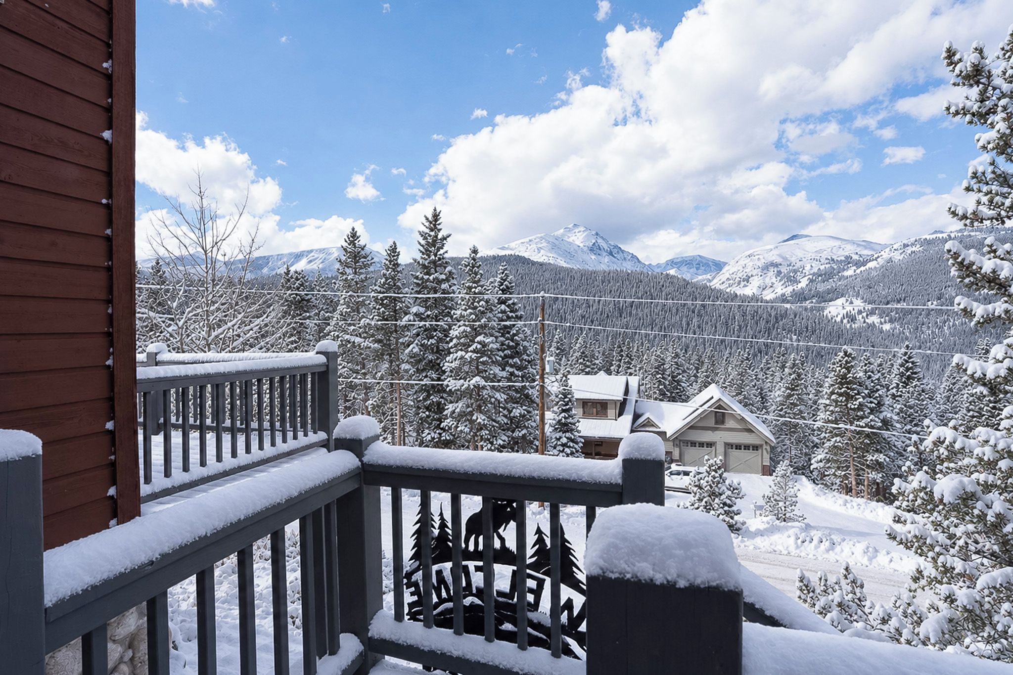 Paesaggio montano innevato con ringhiera di legno e una casa sullo sfondo.