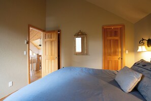Une chambre à coucher avec un lit, une porte, un miroir et une lampe.