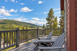 Eine Holzterrasse mit Tisch und Stühlen, mit Blick auf eine Berglandschaft.