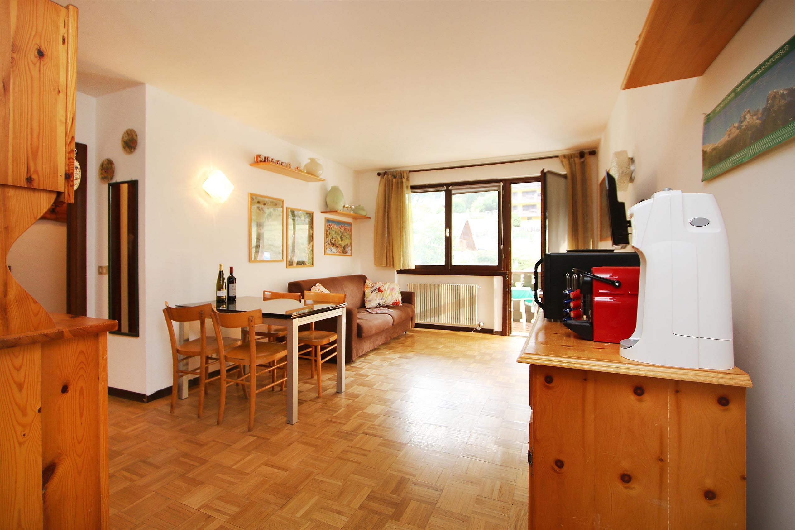 A compact living space with a dining area, a sofa, a radiator, and a kitchen area with a red appliance.