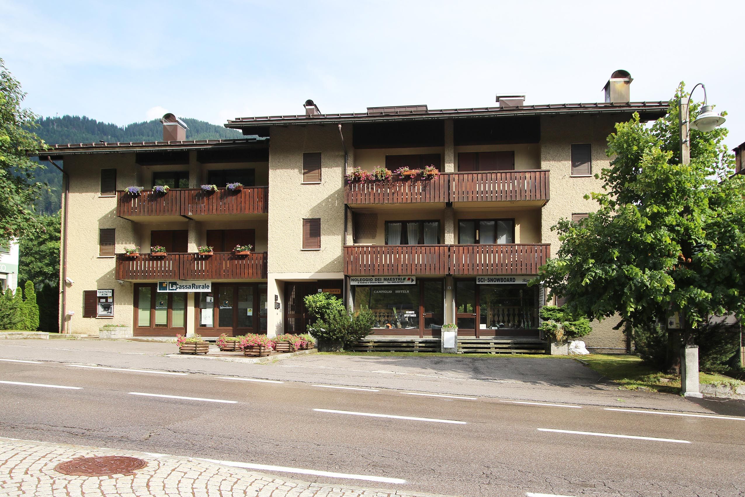 Un hôtel à plusieurs étages doté de balcons, d’un espace extérieur aménagé pour s’asseoir et d’un distributeur automatique de billets bien visible.