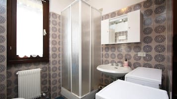 Une salle de bain équipée d’une douche, de toilettes, d’un lavabo et d’un miroir au-dessus du lavabo.