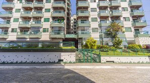 A multi-story residential building with balconies, a gated entrance, and a tiled facade. - Apartment with BBQ 350m from Guilhermina Beach (Praia Grande)