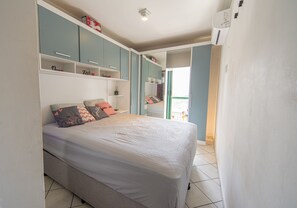 A bedroom with a bed, shelves, and a wardrobe. - Apartment with BBQ 350m from Guilhermina Beach (Praia Grande)