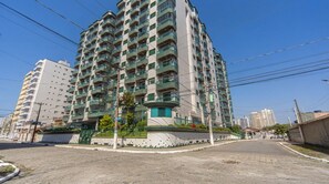Un immeuble résidentiel à plusieurs étages, doté de balcons, situé le long d’une rue pavée, avec d’autres bâtiments en arrière-plan.