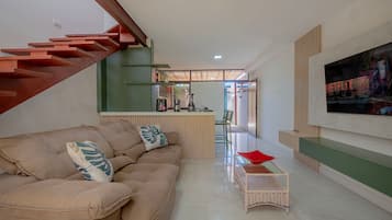 Een moderne woonkamer met een bank, salontafel en een tv aan de muur.