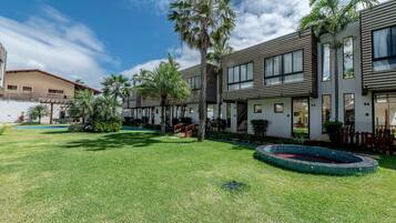 Un edificio residencial con piscina, palmeras y un césped bien cuidado.