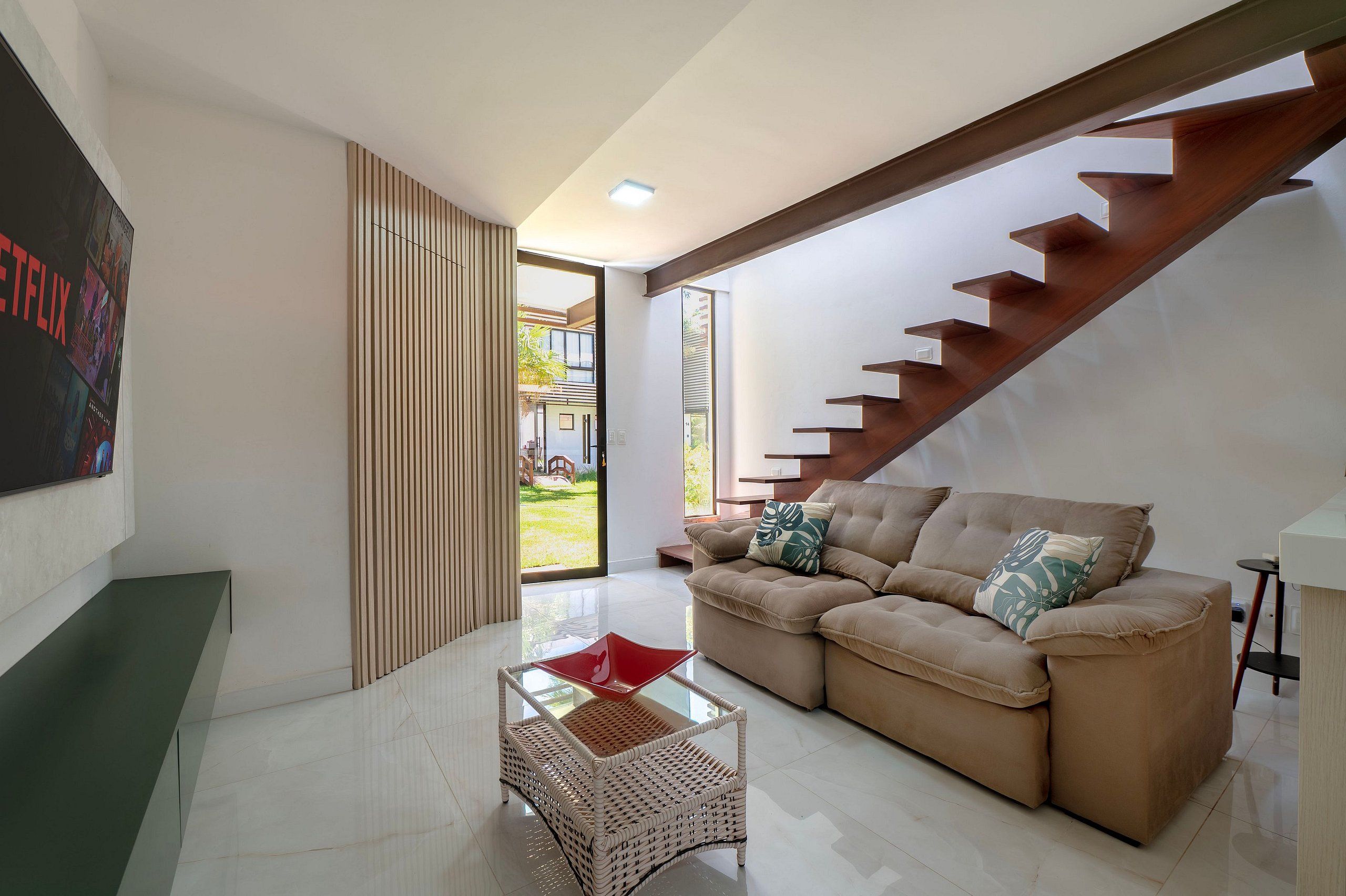 Una sala de estar moderna con un sofá, una mesa de centro de vidrio y una escalera.