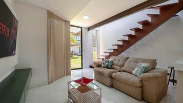 Una sala de estar moderna con un sofá, una mesa de centro de vidrio y una escalera.