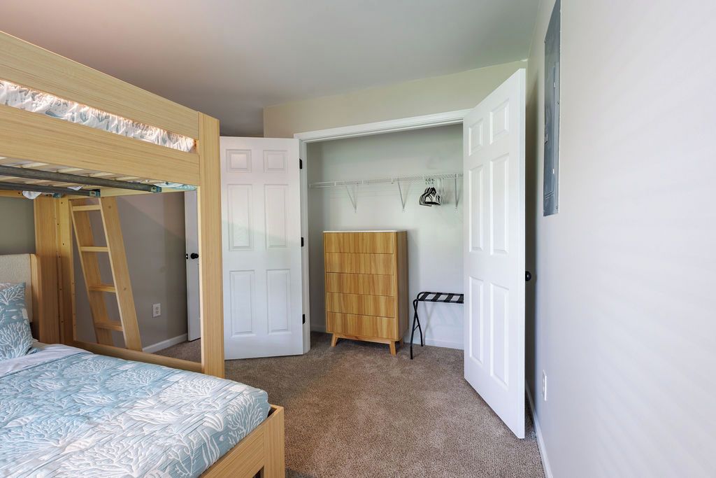 Une chambre avec un lit superposé, une armoire et une porte donnant sur une autre pièce.