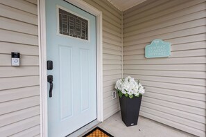 A light blue door with a window, a doorbell, and a sign indicating 'CONWAY COASTAL COTTAGE.'