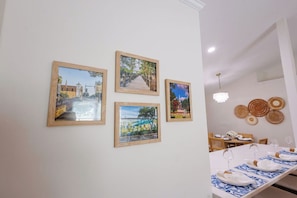 Zona de menjador amb taula ben a punt per a quatre, obra d'art emmarcada a la paret i un penjador.