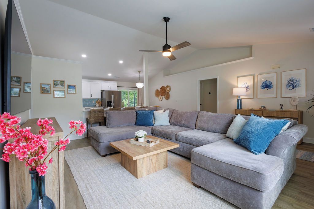 A modern living room with a grey sectional sofa, a wooden coffee table, and a vase with pink flowers.