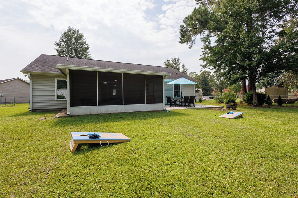 Une maison avec une véranda grillagée, un petit patio avec une table et des chaises, et un trampoline dans le jardin.