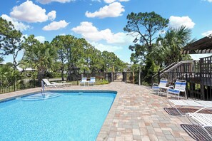 A swimming pool with lounge chairs and a brick patio. - 🌴Boardwalk Bungalow | Steps to Beach | Pool | Pet Friendly🌴 (Cape San Blas)