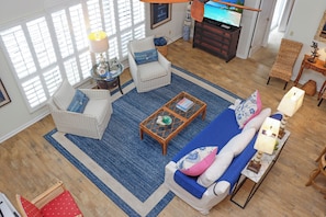 Una sala de estar con sofá, sillas, una mesa de centro y un televisor.